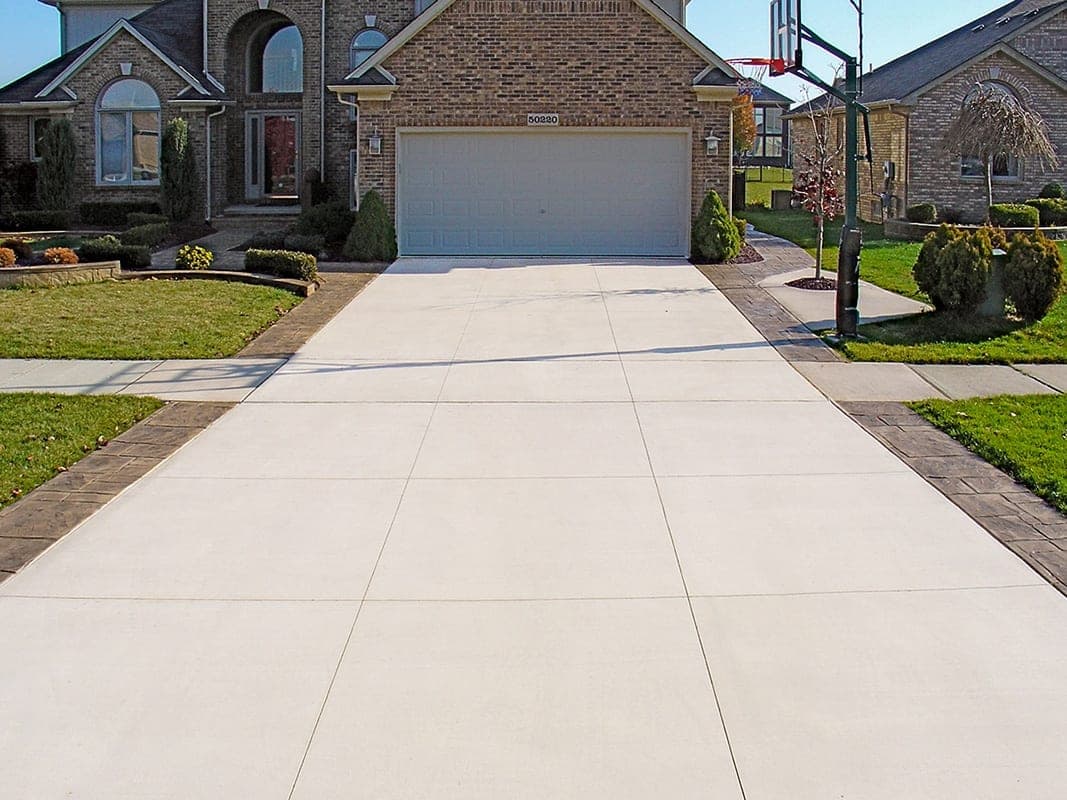 Broom finish concrete driveway in front of a brick home