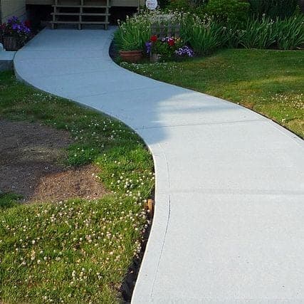 Curved broom finish front walkway through a garden