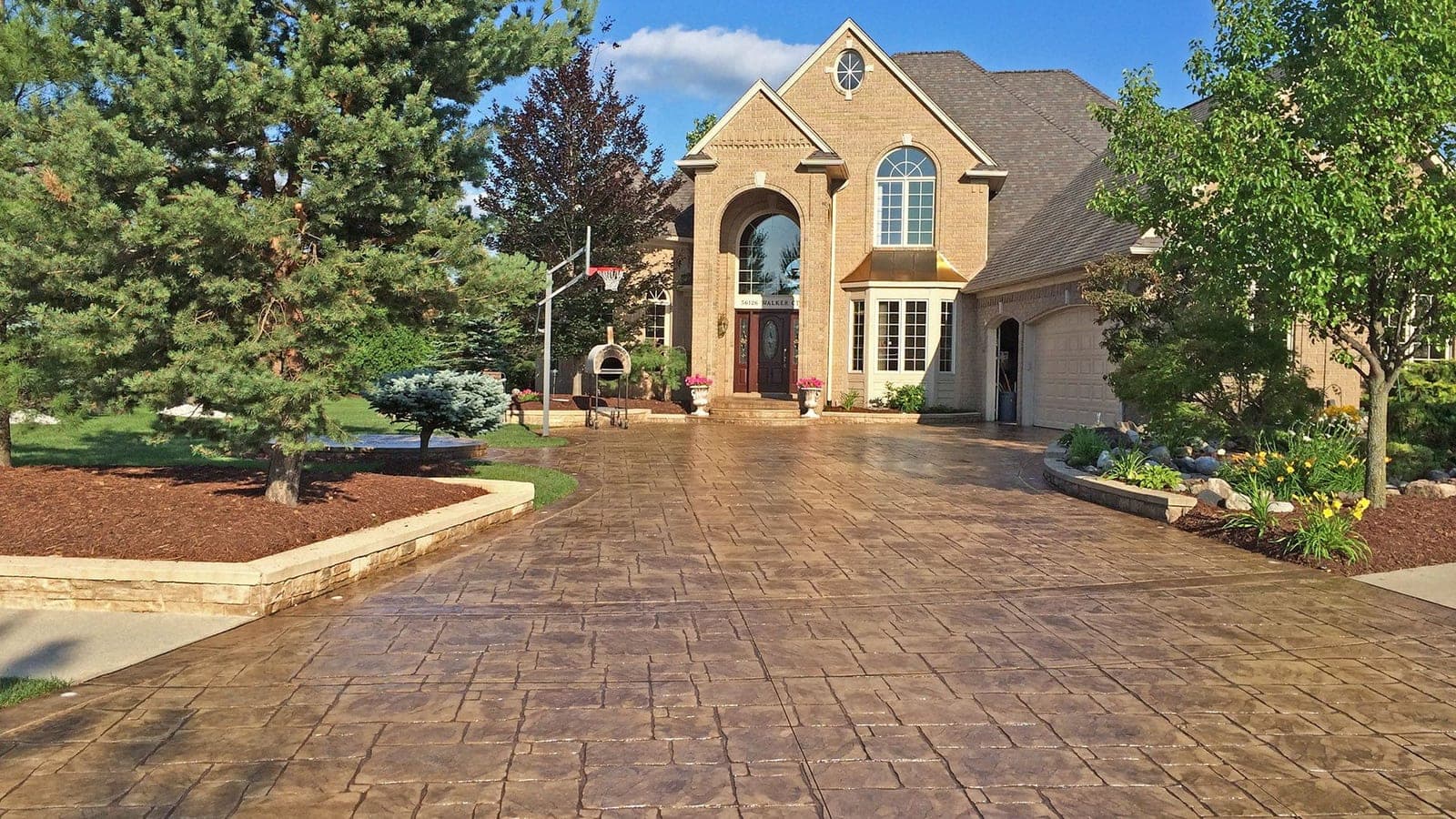 Stamped concrete driveway with a gloss sealer in front of a brick estate home in Southwestern Ontario