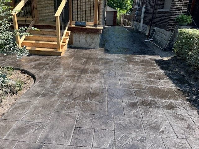 Stamped concrete side-yard walkway beside a deck